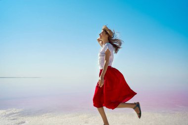 Koşan kadın sonsuz ufuk boyunca yaz seyahati sırasında Pembe Göl 'de boş bir alan.