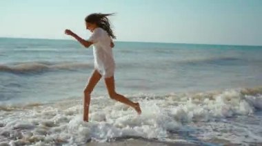 Mutlu, gülümseyen bir kadın ve Corgi köpeği dalgalarla deniz kıyısında koşuyorlar, refah ve özgürlük hissediyorlar..