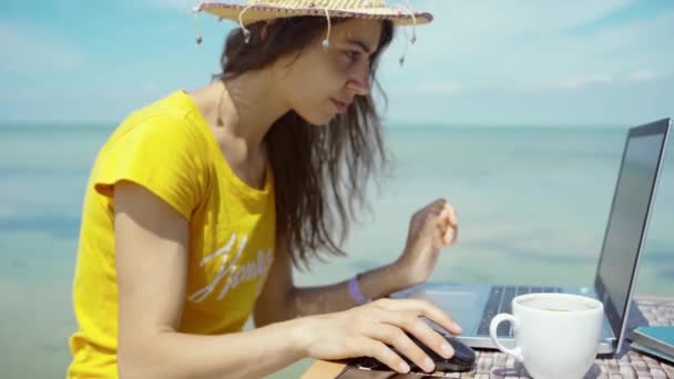 Vista lateral del verano freelancer mujer que trabaja en el ordenador portátil por mar azul durante su viaje — Vídeo de stock