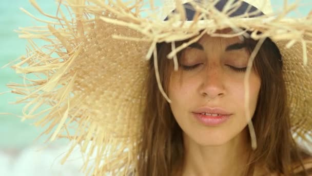 Zbliżenie twarz uśmiechnięta kobieta noszenie słomkowy kapelusz na plaży w słońcu wschód słońca na wybrzeżu. — Wideo stockowe