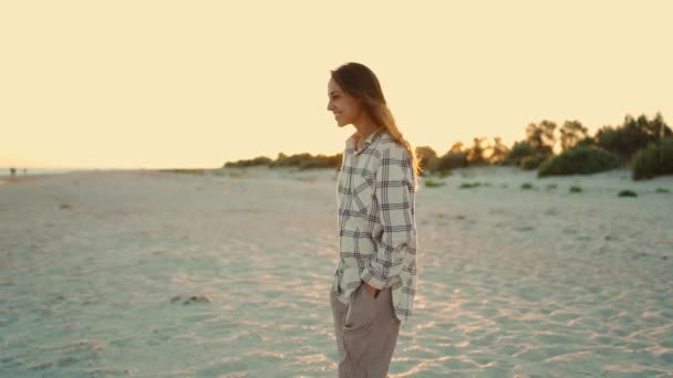 Feliz hermosa mujer de raza mixta hipster disfrutando de caminar en la playa de arena marina salvaje al atardecer con hermoso resplandor de sol en el cabello. — Vídeos de Stock