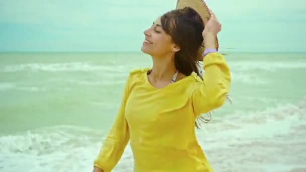 Portré boldog kifejezés nő fúj haj visel sárga ing szórakozás a strandon, és vidáman fut — Stock videók