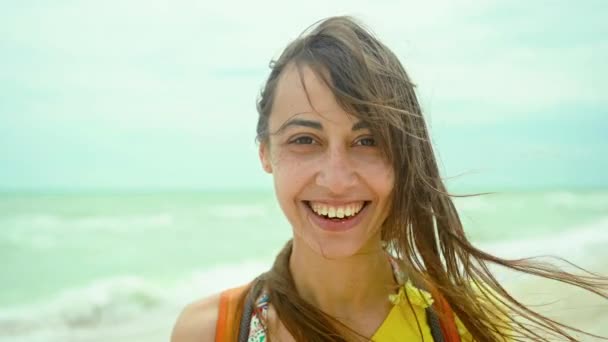 Lachende vrouw genieten van zee strand vakantie, zich goed en gelukkig voelen. meisje dragen geel shirt buiten op zee achtergrond — Stockvideo