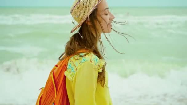 Authenticiteit portret gelukkig jonge vrouw met strohoed dragen geel shirt plezier hebben en het gevoel geluk tijdens het wandelen op het strand — Stockvideo