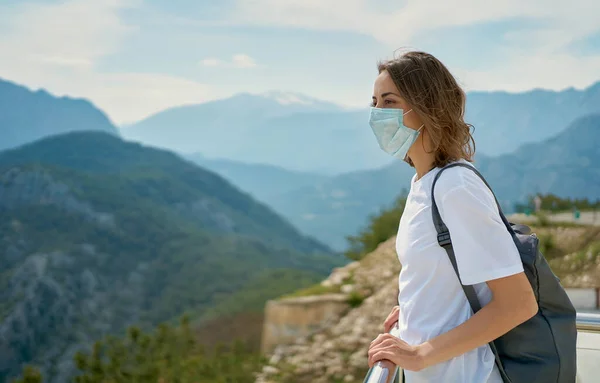 コロナウイルスの流行の間に旅行、山の前で顔マスクを身に着けている女性 — ストック写真