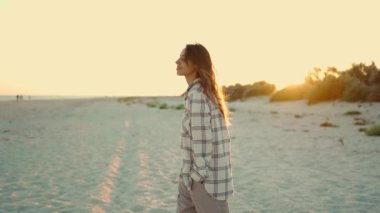 Mutlu, güzel, melez, hippi bir kadın günbatımında kumsalda yürümekten keyif alıyor..
