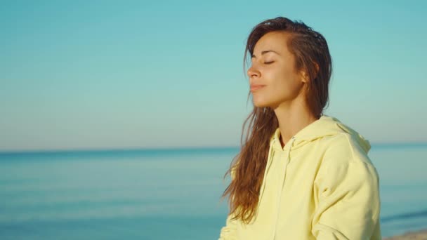 4K portrait en gros plan de belle femme brune mixte en sweat à capuche jaune pratiquant le yoga et la méditation — Video
