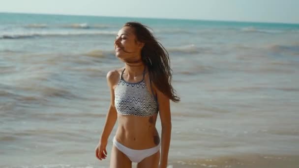 Ralenti du joyeux joyeux slim fitbody femme porter en bikini et profiter du vent et des vagues sur la côte de la mer après la tempête. — Video