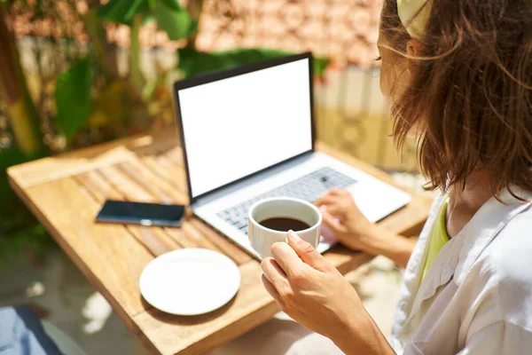 白い空の画面を持つラップトップコンピュータで作業しているリアビューの女性。入力、閲覧、検索 — ストック写真