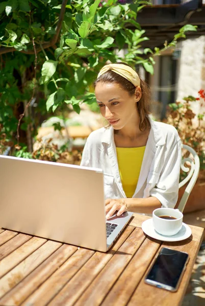 Молодая деловая женщина с ноутбуком, работающая в кафе во время отпуска — стоковое фото