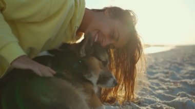 Güzel, mutlu, sevimli, güler yüzlü, sarı kapüşonlu bir kız. Yaz plajında, sevimli bir evcil köpekle.,