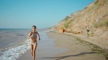 Güzel ince vücutlu bikinili genç fitness kadını gün doğumunda denizde jimnastik yapıyor..
