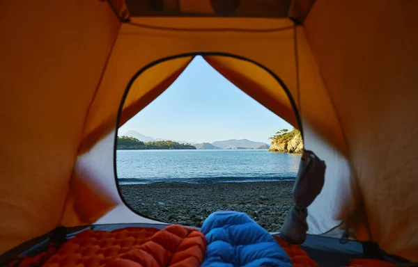Telttailu teltalla rannalla, kaksi turistia makaa makuupussissa näköalalla meren rannalla — kuvapankkivalokuva