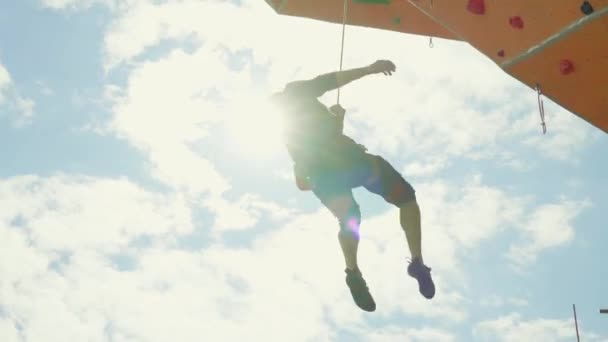 Uomo arrampicatore di roccia appeso alla corda dopo essere caduto dalla via sulla palestra di roccia esterna. uomo deluso guardando le maniglie sul muro, immaginando i movimenti delle mani. — Video Stock