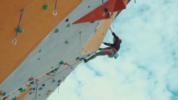 Mulher alpinista trepa rota desafiadora no ginásio de escalada de rocha exterior. — Vídeo de Stock