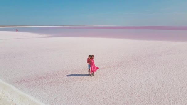 Εναέρια πλάνα του στοργικού ζευγαριού αγκαλιάζει απαλά στη λευκή αλμυρή ακτή της ροζ λίμνης μοιάζει με έρημο. — Αρχείο Βίντεο