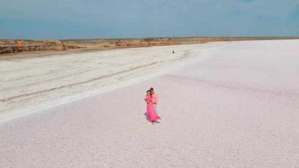 분홍색 호수에 있는 하얀 소금기가 많은 해안에서 다정 한 부부가 부드럽게 포옹하는 느리게 움직 이는 항공 영상 은사 막처럼 보인다. — 비디오