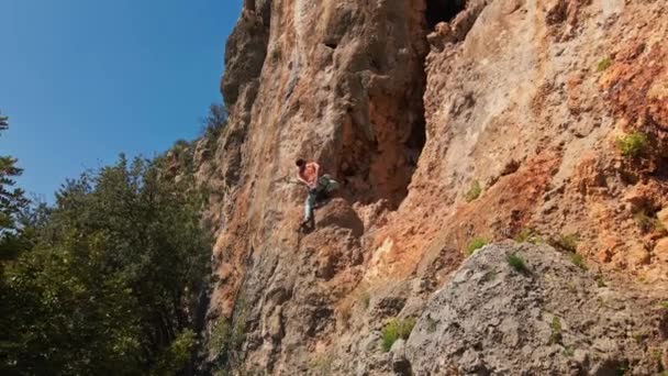 Drone volando desde el acantilado de piedra caliza con escalador de roca en él. hombre sube desafiante ruta en vertical crag — Vídeo de stock