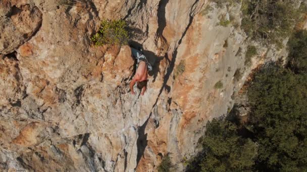 Slow motion back view man rockclimber climbs on overhanging crag (em inglês). homem usando o joelho para o engarrafamento na parede para descansar e cortar corda — Vídeo de Stock