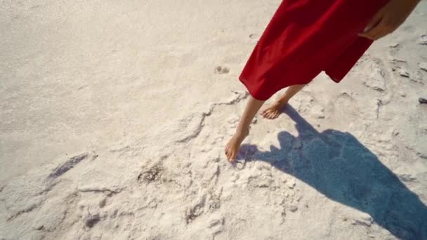 Slow motion beelden van vrouw benen in lange rode rok steken op zout wit strand op mineraal meer kust — Stockvideo
