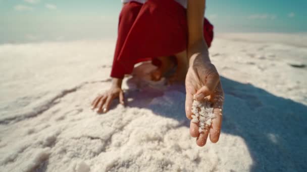 Slow motion footage of woman on dry coast of salt mineral lake. girl touching and holding in hand salt crystals and flakes — Stock Video