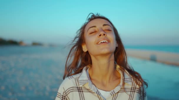 Ao ar livre retrato de feliz atraente mulher de raça mista desfrutando do pôr do sol na praia de areia do mar selvagem com luz solar vermelha no rosto — Vídeo de Stock