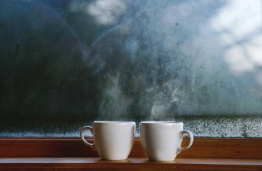 Pencerenin yanında iki fincan sıcak kahve, sabahın erken saatlerinde, uyanma kavramı.