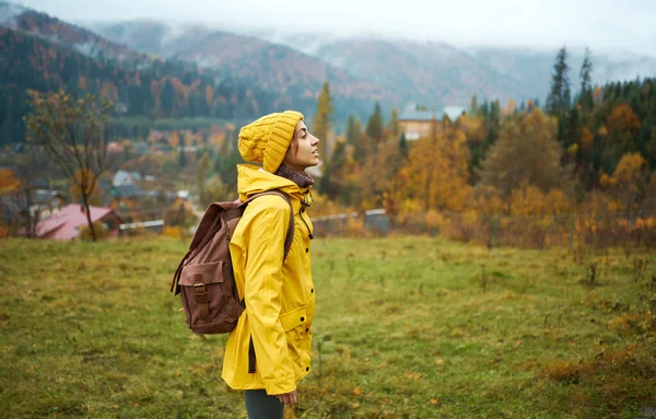 Turistkvinne i gult står på vakker fjellutsikt, gjør seg klar til å gå – stockfoto