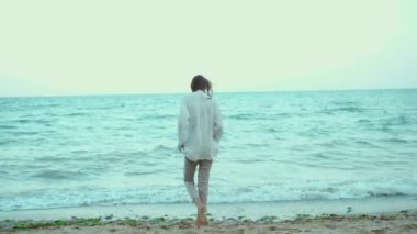 Deniz suyunda dalgalarla yürüyen güzel bir yaz kadını. Özgürlük ve cennet kavramı