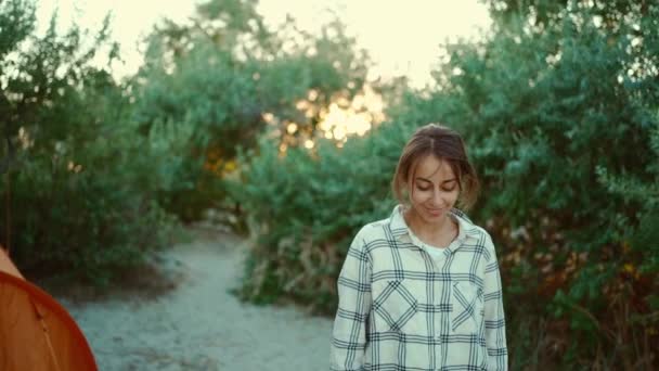 Slow motion portret van gelukkige mooie vrouw met gebruinde huid wandelen buiten uit groene struiken op wilde zee zand strand bij zonsondergang — Stockvideo