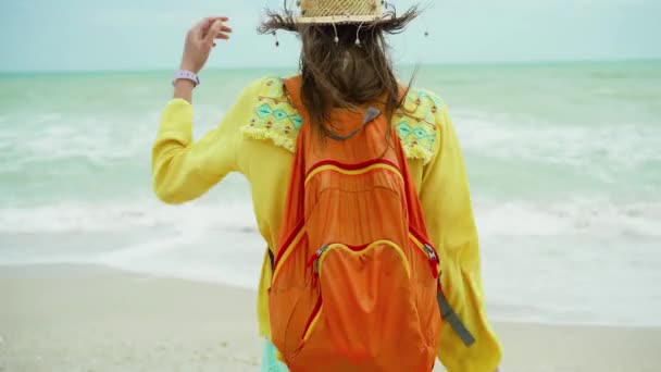 Mujer en verano ropa brillante con los brazos abiertos de pie en frente hermosa vista del paisaje marino, disfrutando del clima ventoso tormenta en la playa — Vídeos de Stock