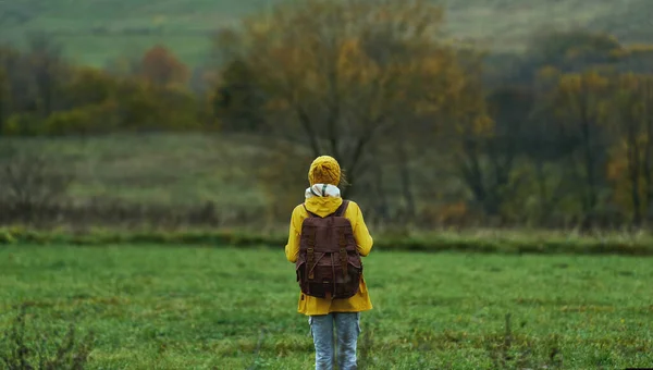Turista de pie en el césped verde entre colinas. Clima frío, nublado otoño vista de la naturaleza — Foto de Stock