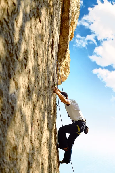 Rock climber climbing up a cliff — Stock Photo, Image