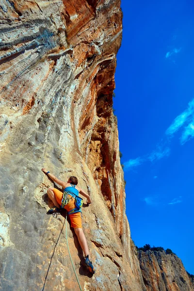 Rock climber climbing up a cliff — Stock Photo, Image