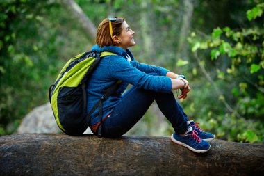 Woman hiker smiling standing outside in forest with backpack clipart