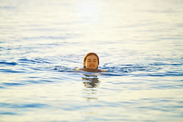 Lächelndes Mädchen schwimmt im Morgengrauen im Meer — Stockfoto