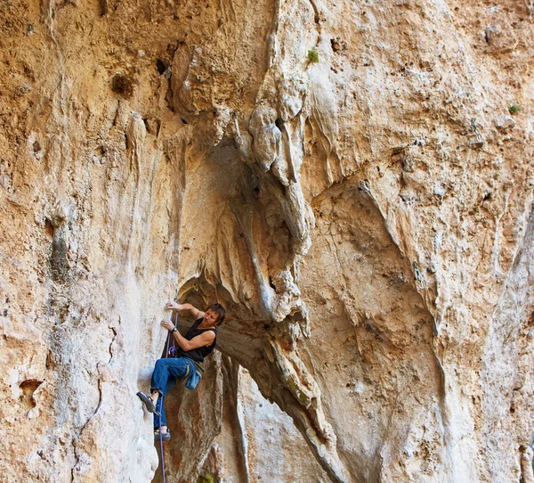 Rock climber climbing up a cliff — Stock Photo, Image