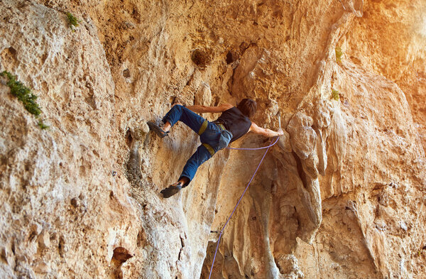 Rock climber climbing up a cliff