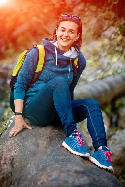 Γυναίκα πεζοπόρος χαμογελώντας στέκεται έξω στο δάσος με σακίδιο — Φωτογραφία Αρχείου