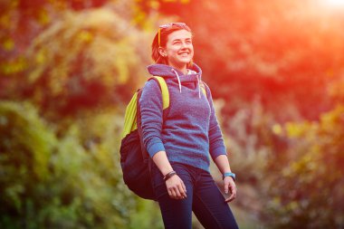 Sırt çantası ile orman dışında ayakta gülümseyen kadın uzun yürüyüşe çıkan kimse