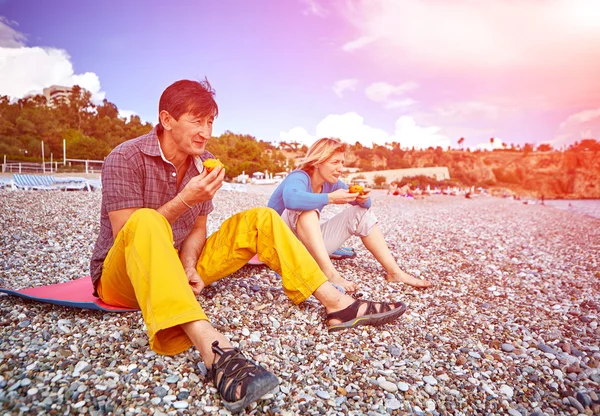 Pari rannalla syöminen persimmons — kuvapankkivalokuva