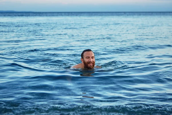 Glimlachende man zwemt in de zee bij zonsopgang — Stockfoto