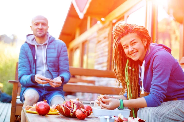 Pareja joven en el jardín comiendo granadas — Foto de Stock