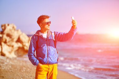 Gezgin selfie deniz ve mavi gökyüzü karşı erken sabah yapım sırt çantası ile