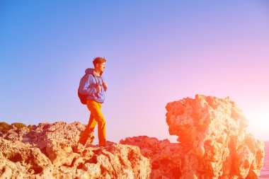 Gezgin ile deniz ve mavi gökyüzü karşı Uçurumdaki erken sabah saat ayakta sırt çantası