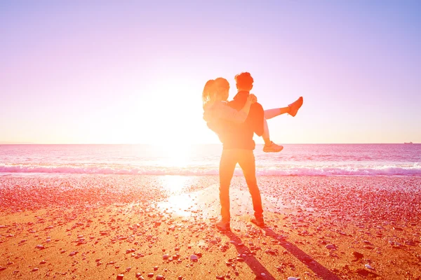快乐迷人的男人和女人在阳光灿烂的沙滩上蓝天漫步 男人牵着女人的手 — 图库照片