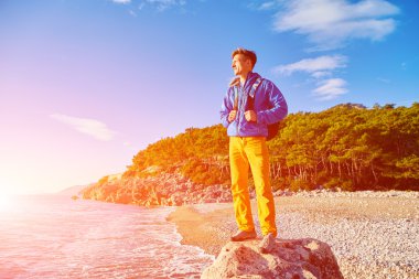 Gezgin ile deniz ve mavi gökyüzü karşı Uçurumdaki erken sabah saat ayakta sırt çantası
