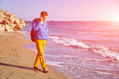 Deniz ve mavi gökyüzü karşı sahilde erken sabah saat ayakta ve telefonla konuşurken genç adam