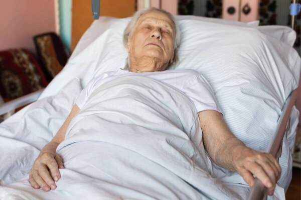 Sick senior woman sleeping lying in medical bed at home. Concept: age, social help lonely, health care and people. Close up.