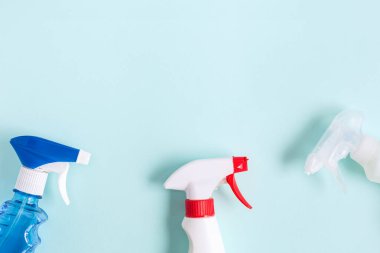 Düz kompozisyon. Mutfak, banyo ve diğer odalardaki farklı yüzey için deterjan ve temizlik aksesuarları. Mavi arkaplanda mesaj ya da logo için boş yer. Temizlik hizmeti konsepti. Üst görünüm.